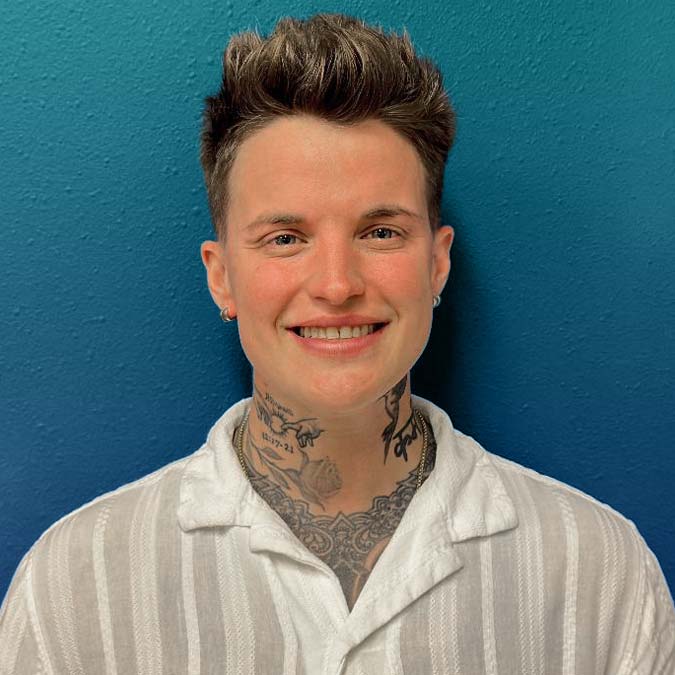 Smiling person with short hair, white shirt, and neck tattoos embodies hope in mental health recovery.